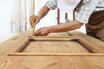 carpenter work the wood, measuring a thickness with angle square on wooden vintage door