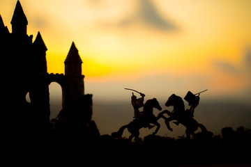 Fototapeta na wymiar Medieval battle scene with cavalry and infantry. Silhouettes of figures as separate objects, fight between warriors on dark toned foggy background with old gothic castle