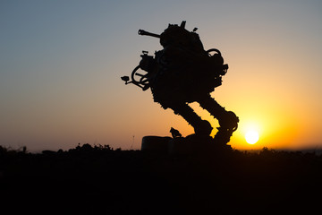 Silhouette of giant robot. Futuristic tank in action at sunset.