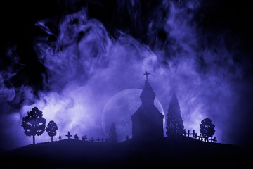 Fototapeta na wymiar Scary view of zombies at cemetery dead tree, moon, church and spooky cloudy sky with fog, Horror Halloween concept.