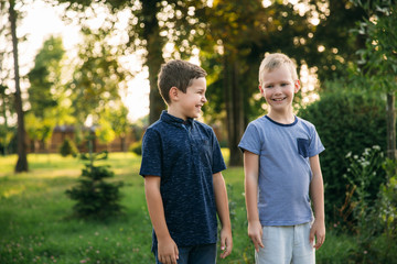 Obraz premium Two children boys friends walking in the park on a sunny summer day