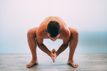 Fototapeta na wymiar Yoga. Young man doing yoga exercise isolated on a white background. Yogi master workout on white urban studio. Yoga lifestyle healthy concept.