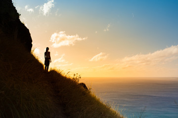 Woman watching the sunset on the edge of cliff. Feeling at peace and serenity. 