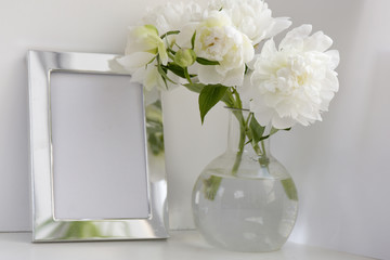 White peony in glass vase on white background. Metal frame.
