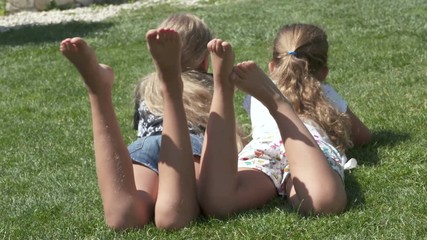 Little girls barefoot lying on the lawn on a warm summer day.