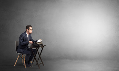 Man working hard on a typewriter in an empty space
