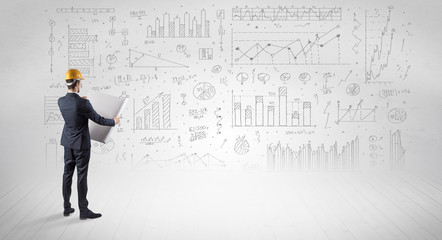 Engineer with construction helmet holding a plan and standing with graphs, charts and reports on the background