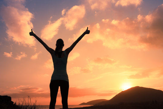 Winning, success , and life goals concept. Young woman with arms in the air giving thumbs up.
