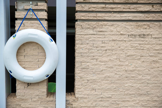 Close up lifebuoy, all water rescue emergency equipment. white lifebuoy on brick wall. nearby the swimming pool, image for background, wallpaper, objects and copy space. for safety and rescue.