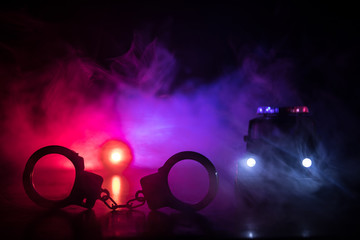 Closed handcuffs on the street pavement at night with police car lights