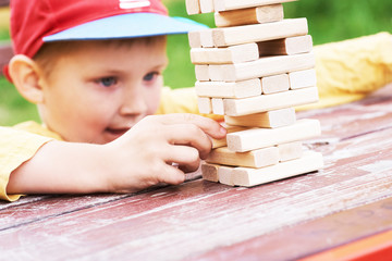 Caucasian kid is playing wood blocks tower game for practicing physical and mental skill.