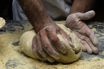 Male hands kneading dough on sprinkled