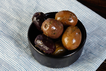 Black and green olives in wooden plate on wooden background. Salted olives. International cuisine. Harvesting.