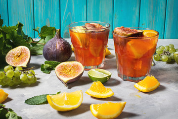 Cocktail fruit sangria with apples, orange, figs, grapes on concrete table
