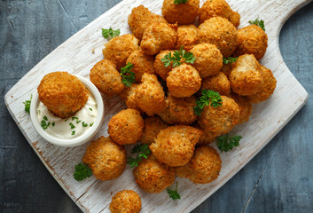 Homemade Breaded Garlic Mushrooms with sour cream and parsley on white wooden board