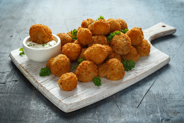 Homemade Breaded Garlic Mushrooms with sour cream and parsley on white wooden board