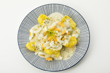 Dillkartoffeln, gekochte Kartoffeln, Dill-Rahm-Sauce und gekochte Eier, serviert auf einem blauen Teller auf weissen Untergrund, Freisteller