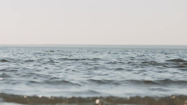 Slow motion handheld of waves on a beach on a windy sunny day