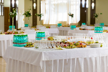 Served tables at the Banquet. Desserts, fruit and pastries on the buffet. Glassware and mineral water bottles. Roses in a jug. Catering.