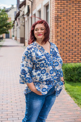 Portrait of attractive plus size mature woman in casual style walk at city at good sunny autumn day...