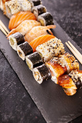 Plate with variety of sushi on a dark stone background. Healthy cuisine