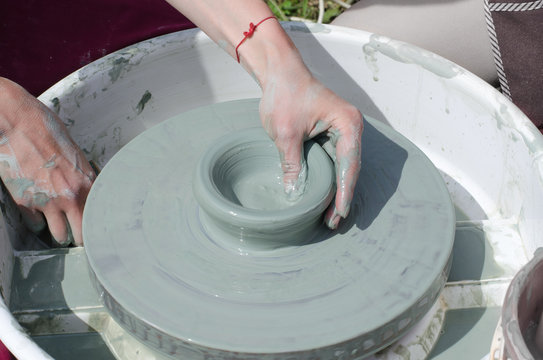 Ceramic workshop - the girl makes a pot of clay on a potter's wheel. Hands closeup