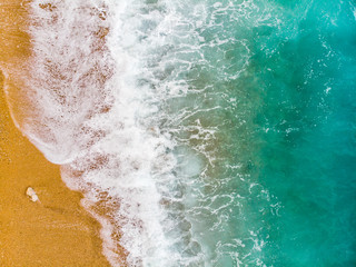 Fototapeta na wymiar top view of a wave of sea foam on a sandy beach of the ocean