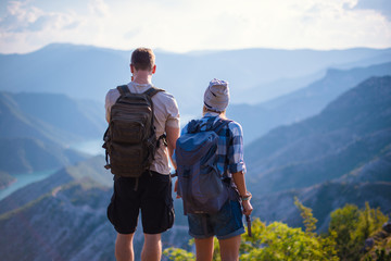 Obraz premium Marveling the view on the top of the mountain. Young couple at the summit enjoying the view.