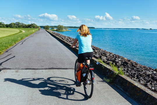 Blonde woman is cycling along the bike path around the Lac du Der Chantecoq in France