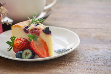 Mixed berry butter cake with fresh blueberries and strawberries on white plate put on wood table in side view copy space. Delicious and moist with sweet and sour taste in homemade bakery concept.