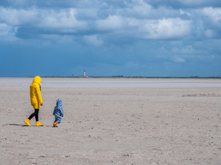 Frau geht mit ihrem Kind am Strand von St. Peter-Ording spazieren