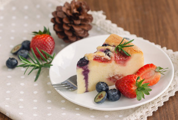 Mixed berry butter cake with fresh blueberries and strawberries on white plate put on wood table in side view copy space. Delicious and moist with sweet and sour taste in homemade bakery concept.