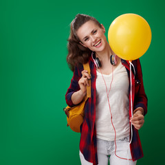 smiling student woman with yellow balloon on green background