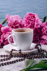A cup of coffee with peonies on the table