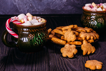 A cup full of marshmallow with lollipops and biscuits