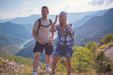 Breathing the fresh mountain air and taking photographs. Young couple at the summit enjoying the view.