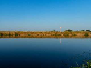River landscape. Beautiful view of the full-flowing river from the high steep Bank, overgrown with grass. The blue surface of the water, cloudy sky and green grass on the opposite Bank of the river
