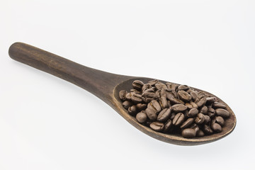 Raw coffee in wooden ladle on white background