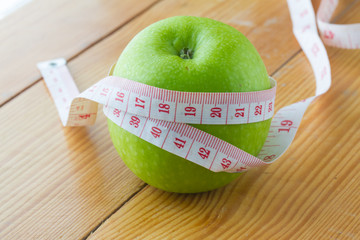 green apple and  measuring tape on wooden background.