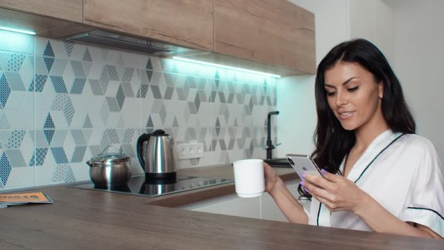 Woman come to wooden table, sit and work on smartphone, iphone x and drink coffee