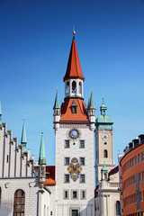 Obraz premium Ornate Gothic bell tower of former town hall Altes Rathaus in Marienplatz square in historic center of Munchen Altstadt district with tower of Heilig-Geist church in background, Bayern Germany Europe