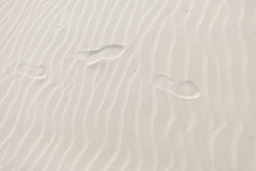 Fototapeta na wymiar Top view of footprints in the white sand waves beach background.