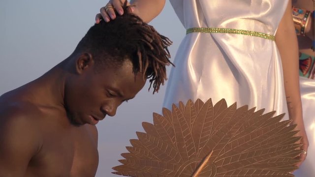 The slave kneels fan, while the great queen of Egypt caress him on the head