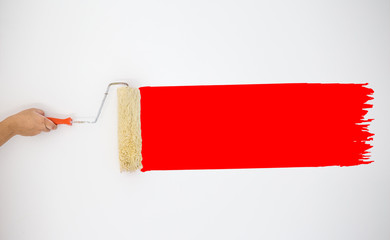 Painter's hand held roller to painting Red color paints on the grey wall. image for add text,...