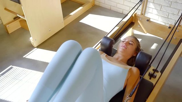 Slim woman doing doing exercises on a special machine for fitness.