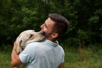 Friendship of man and dog. Happy young man is playing with his friend - dog Labrador