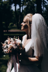 A bride in a white dress is holding a beautiful wedding bouquet.