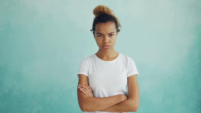 Portrait of angry African American lady looking at camera, frowning and expressing disappointment and disapproval standing with arms crossed and breathing heavily.