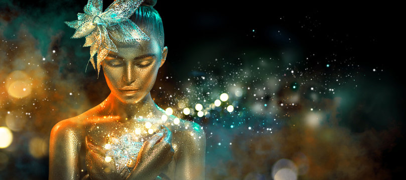 Fashion model woman in colorful bright golden sparkles and neon lights posing with fantasy flower. Portrait of beautiful girl with glowing makeup