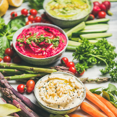 Healthy raw summer vegan snack plate. Chickpea, beetroot, spinach hummus dips with colorful fresh vegetables and greens, square crop. Clean eating, dieting, vegan or vegetarian party food